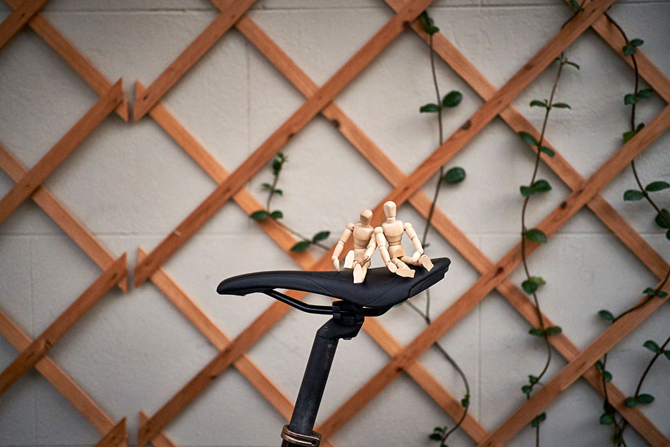 Couples therapy example with wooden figures sitting on a bicycle sattle